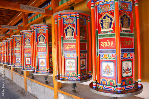 prayer wheels : Buddhist praying wheels against the Labrang Monastery,Xiahe,Gansu province,China photo