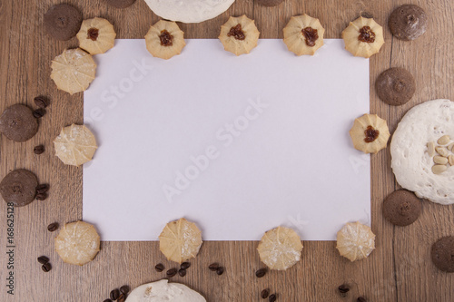 White paper card and cookies on creamy wooden background