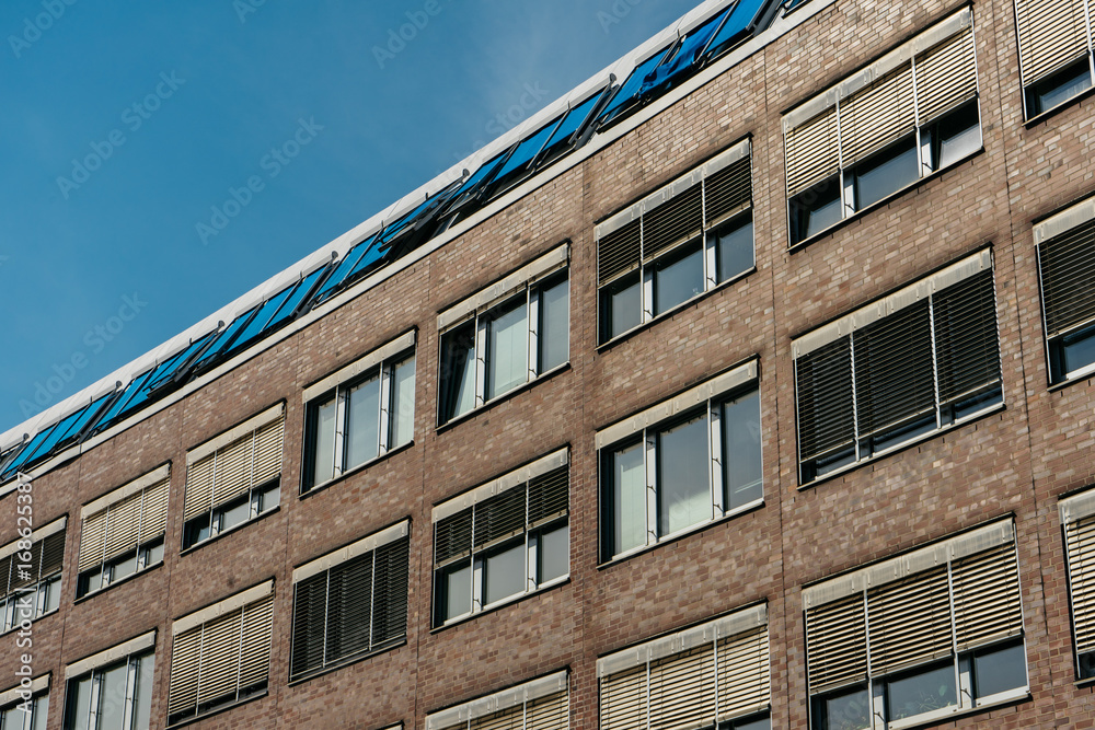 Fototapeta premium brick office building with blue blinds on the rooftop