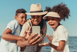 mother with kids taking selfie on beach