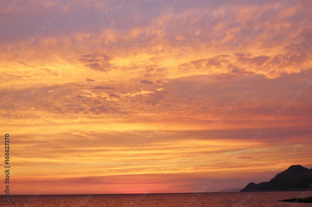 Naklejka premium Jasne kolorowe niebo zachód słońca nad morzem. Na wybrzeżu Dobra Voda, Czarnogóra, południowo-wschodnia Europa.