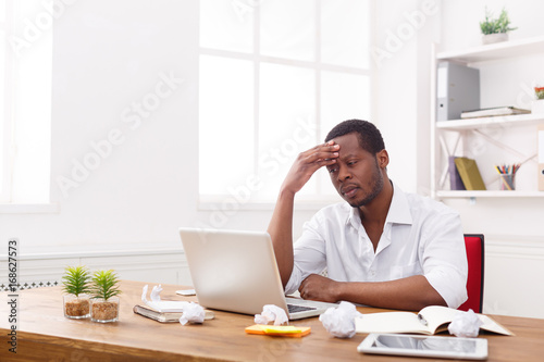 Tired black businessman in office, work with laptop