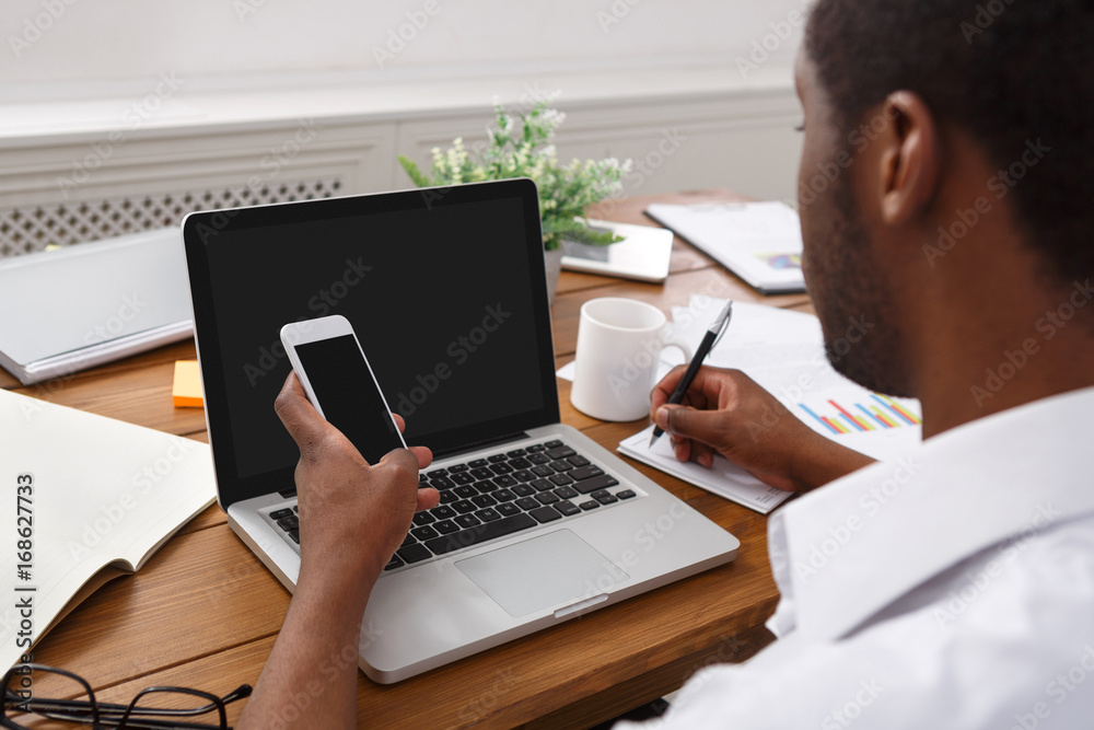 African-american businessman in office with mobile and laptop African-american businessman in office with mobile and laptop