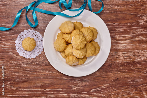 Wheat cookies on white plate and white napkin with blue ribbon on brown wooden background photo