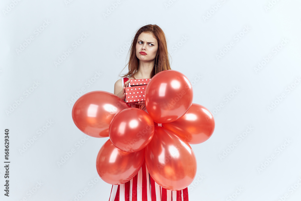 Beautiful young woman on a white background holds balloons and a gift Beautiful young woman on a white background holds balloons and a gift