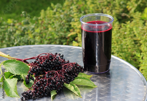 elder juice and elder berries on a table outdoors