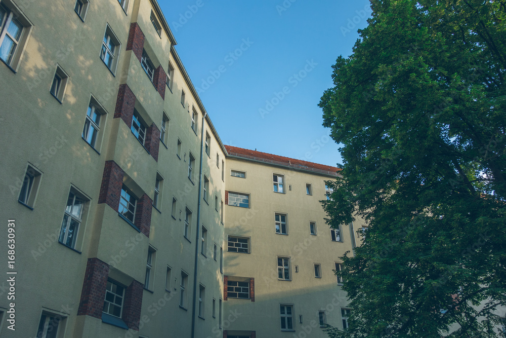 yellow apartment block with brick ornaments and green tree