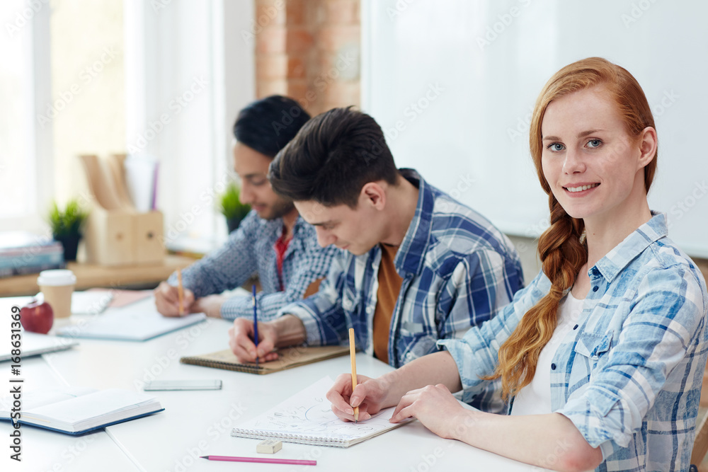 Young learners of high school making notes or sketching in notepads Young learners of high school making notes or sketching in notepads