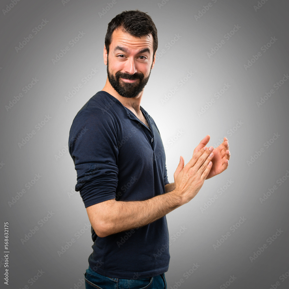 Handsome man with beard applauding on grey background Handsome man with beard applauding on grey background