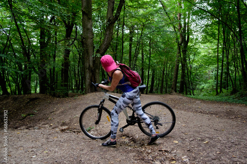 young girl in sport wear with bicycle riding in forest in summer