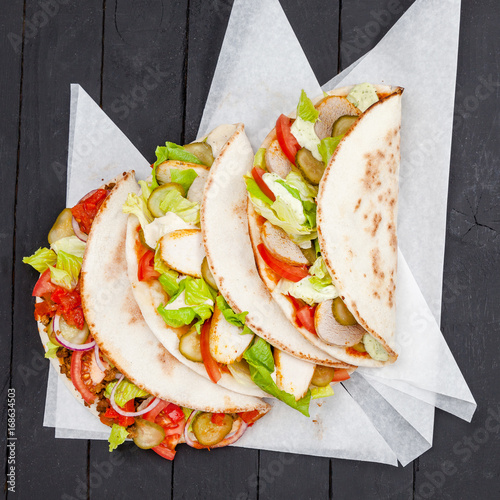 Street food calzone, stromboli wrapped in paper on a black background