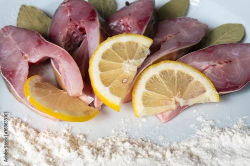 Fillet of fresh fish carp on a plate with spices and flour. photo