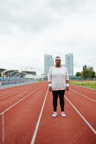 Young plump woman in activewear standing on one of racetracks