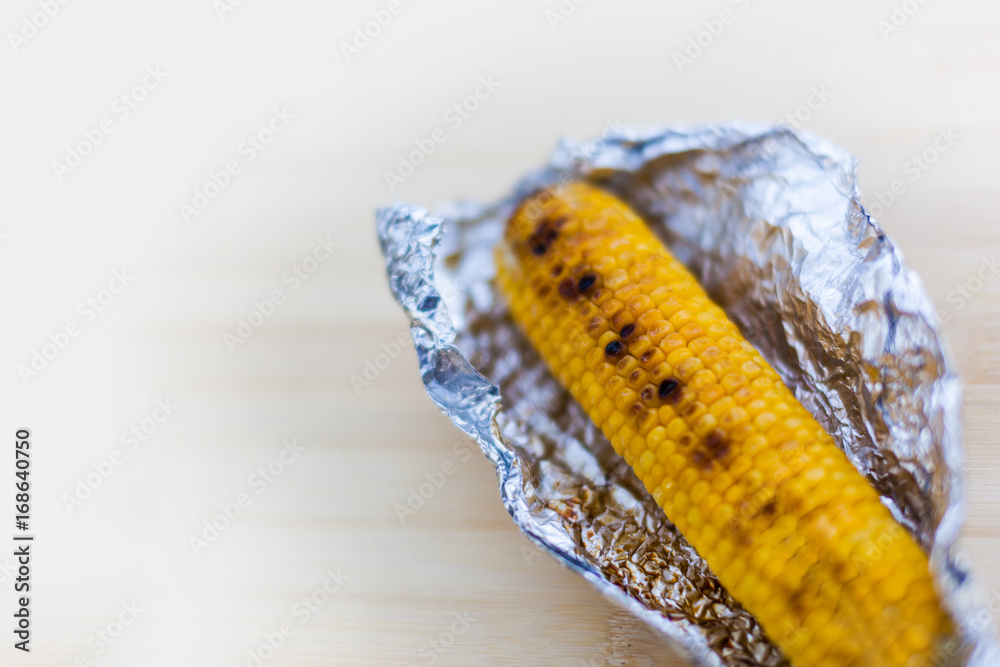 Fototapeta premium Baked yellow corn in foil on white background