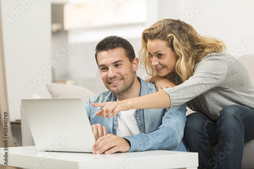 Happy young couple watching internet on their computer / laptop.