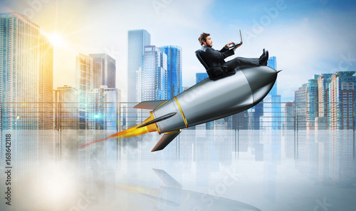 Fast internet concept with a businessman with laptop over a rocket photo