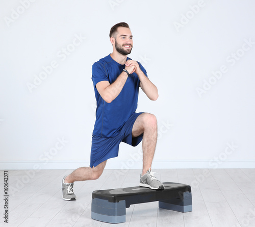 Young sporty man training legs with stepper in gym