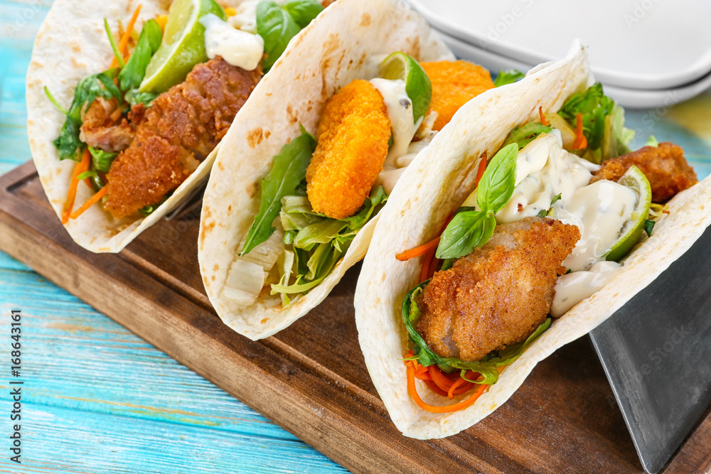 Delicious fish tacos on wooden board on blue background Delicious fish tacos on wooden board on blue background