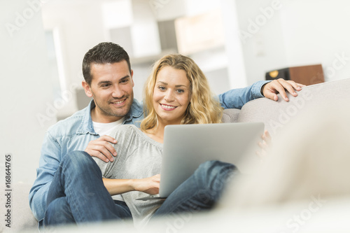 Happy young couple watching internet on their laptop