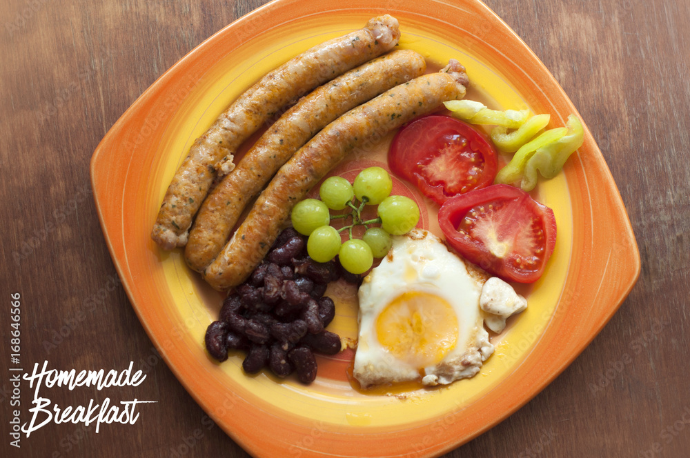 English breakfast in plate with fried egg and meat sausages, beans, grapes, sliced tomatoes and pepper