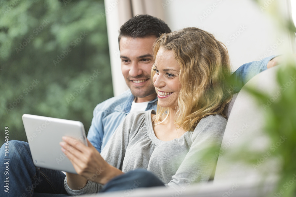 Happy young couple watching internet on their tablet