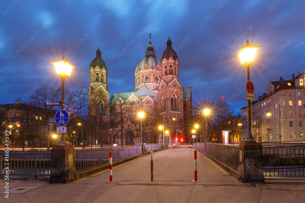Fototapeta premium Saint Lucas Church, the largest Protestant church in Munich, and bridge across Isar River at night, Bavaria, Germany