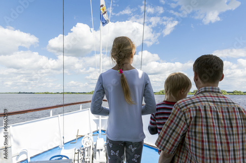 man, a father with two children, a boy and a girl on the deck of the ship on the river photo