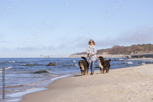 woman with bernese mountain dog on sea beach