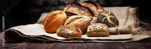 Different kinds of bread and bread rolls on wooden table