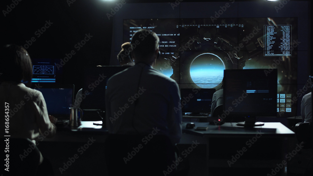 Back view of people working and managing flight in mission control center. The spacecraft lands on the moon Back view of people working and managing flight in mission control center. The spacecraft lands on the moon