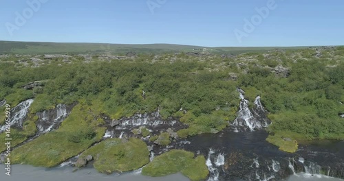 Flying diagonally over Hraunfoss lava spring waterfall glacial river Iceland aerial 4k photo