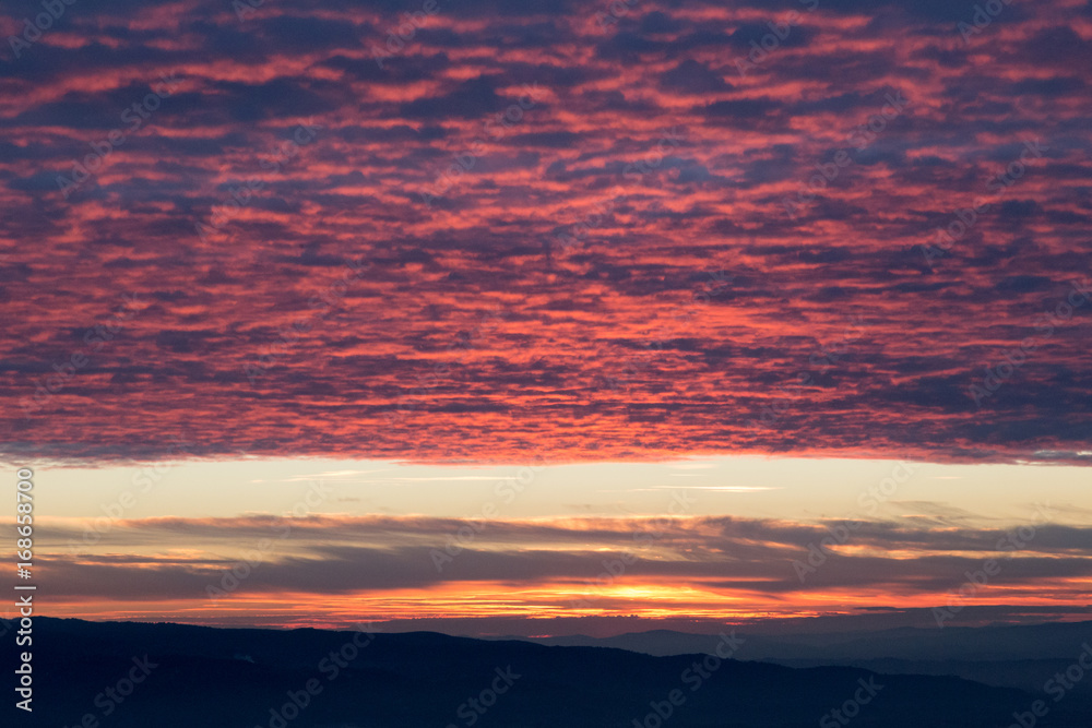 A surreal rooftop of red clouds, reflecting sunset light