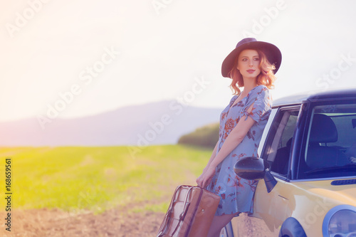 woman with map and suitcase near a yellow car