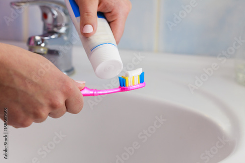 Hand applied toothpaste on toothbrush