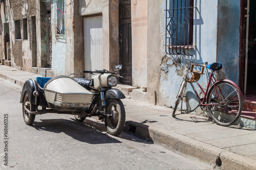 Motorcycle qith a side car and bicycle on the street in Camaguey, Cuba photo