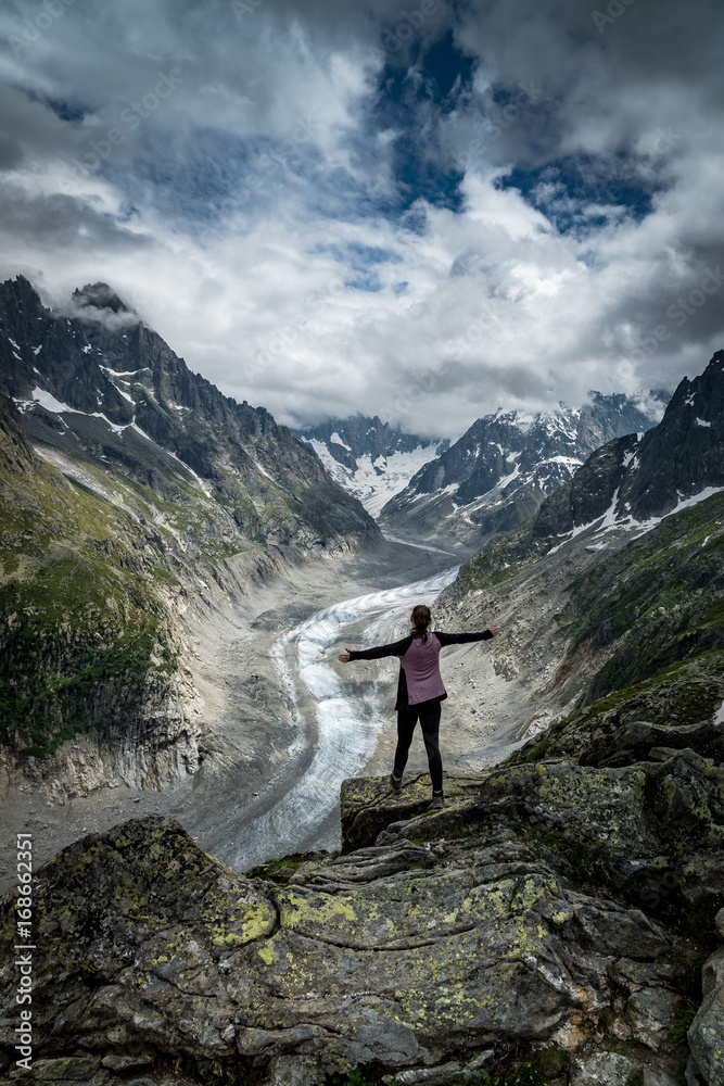 Naklejka premium Wanderin mit ausgestreckten Armen geniesst Aussicht auf den Mer de Glace Gletscher bei Montenvers, Chamonix