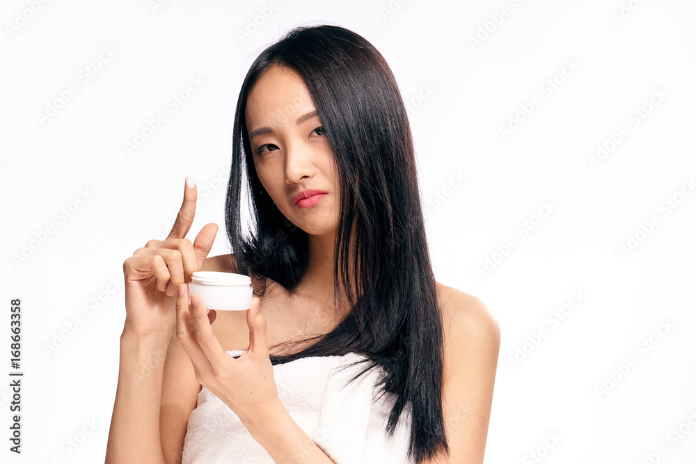 Beautiful woman on white isolated background holds cosmetic cream, spa, asian Beautiful woman on white isolated background holds cosmetic cream, spa, asian
