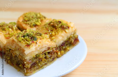 Close-up of Baklava Sweets with Pistachio Nuts Served Wooden Table, Blurred Background 