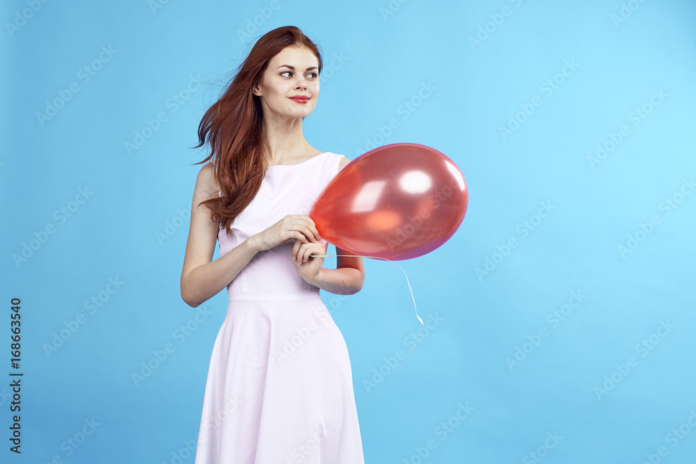 Beautiful woman on a blue background in a dress holding a balloon, blank space for copy Beautiful woman on a blue background in a dress holding a balloon, blank space for copy