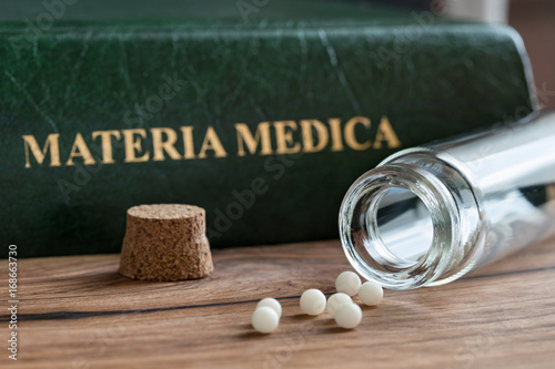 A bottle of homeopathic remedies with a materia medica photo