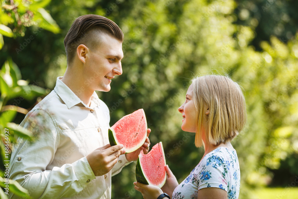 Obraz premium Couple is eating watermelon in a summer park