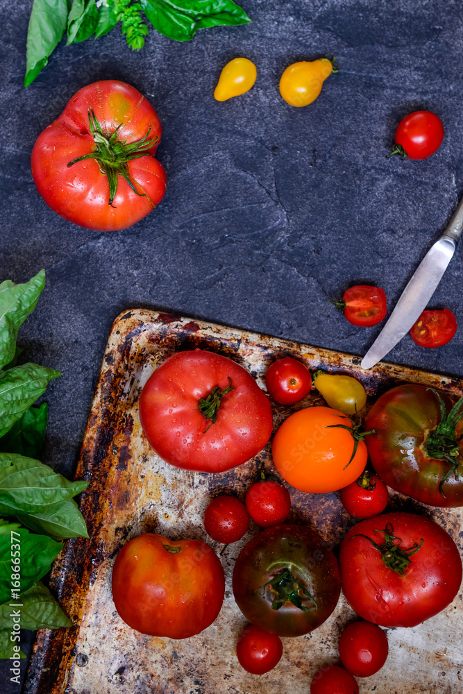 Top view colorful tomatoes, red tomatoes, yellow tomatoes, orange tomatoes with water drops on the dark concrete background. Space for text, selective focus