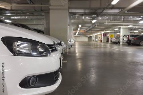 underground parking perspective with the close up fragment of white car in the left corner © Pereginskaya