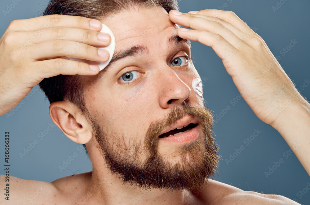 Obraz premium Man with a beard on a gray background, cosmetic cream, portrait, sponge