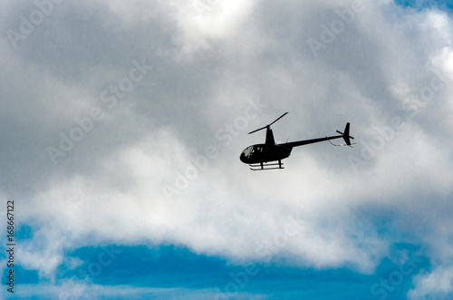 helicopter flying to the left in the clouds above a blue sky
