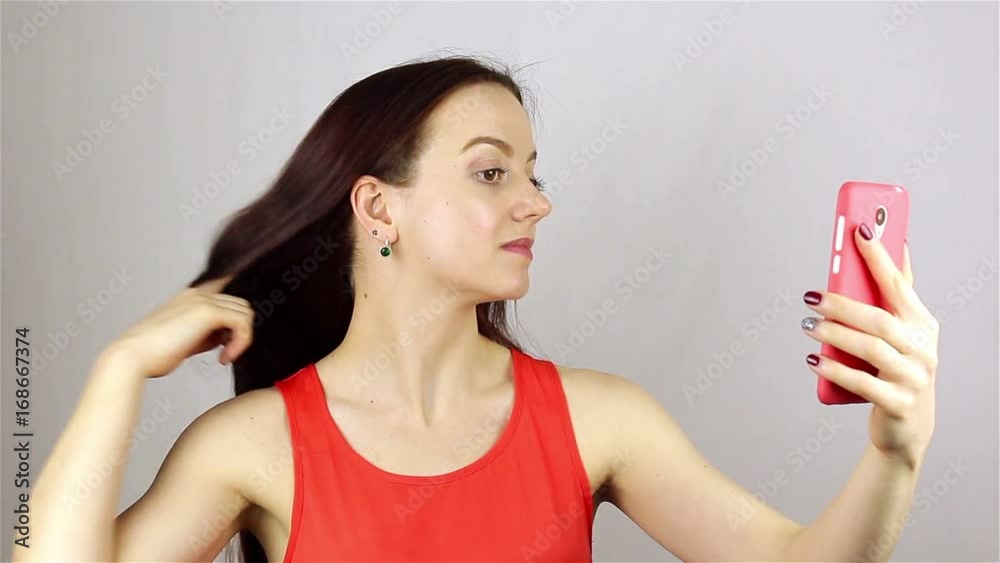 The girl straightens her hair and looks at the phone. The girl straightens her hair and looks at the phone.