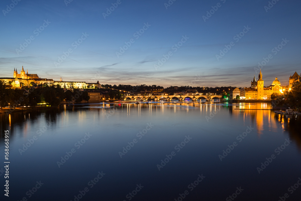 View of the lit Prague (Hradcany) Castle, Charles Bridge (Karluv most), buildings at the Old Town and their reflections on the Vltava River in Prague, Czech Republic, at night.
