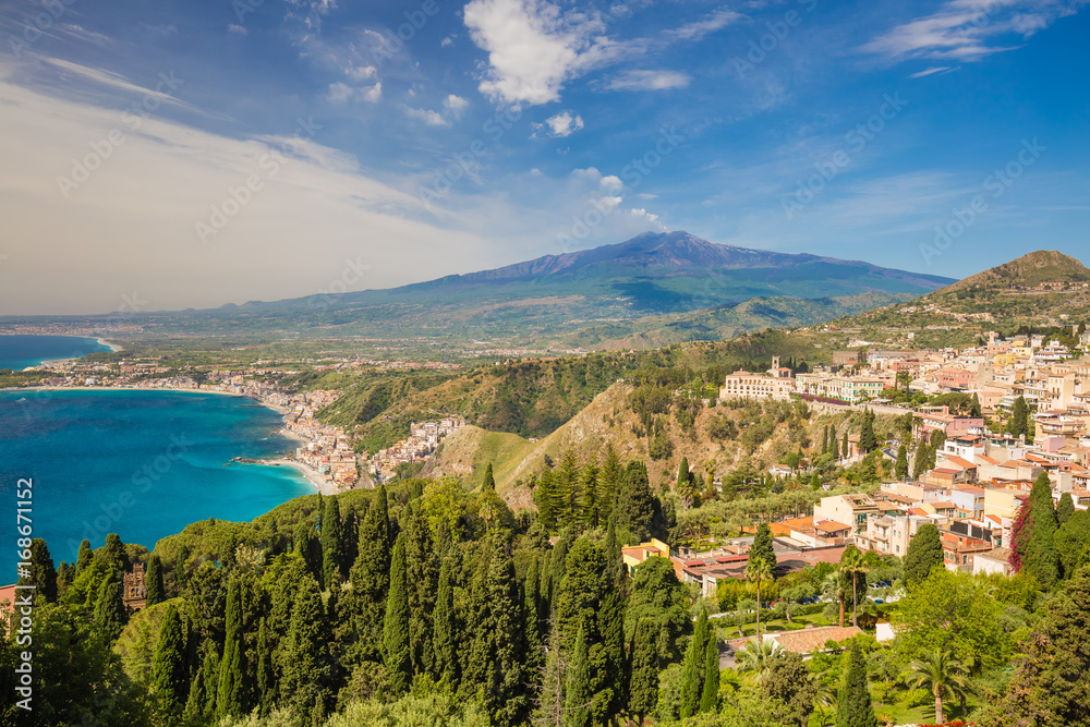 Panoramic view of beautiful town of Taormina, with green foreground and blue sky, Sicily island, Italy