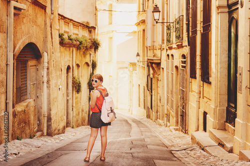 Funny little girl traveler walking on the streets of Provence, wearing backpack. Travel with kids, family vacation on south of France, image taken in Montpellier