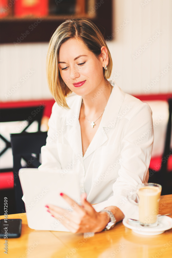Beautiful young business woman working with tablet pc in a coffee shop Beautiful young business woman working with tablet pc in a coffee shop